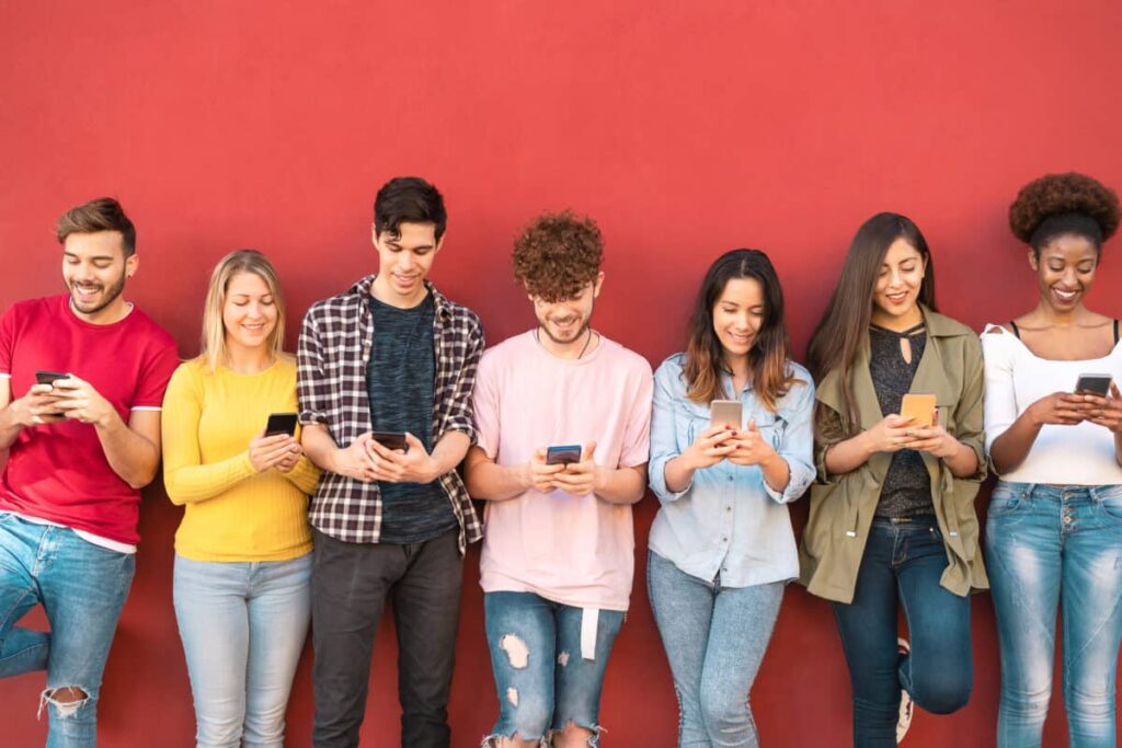 BCE or TELUS: Which TSX Dividend Stock Is a Better Buy Now? young people stare at smartphones