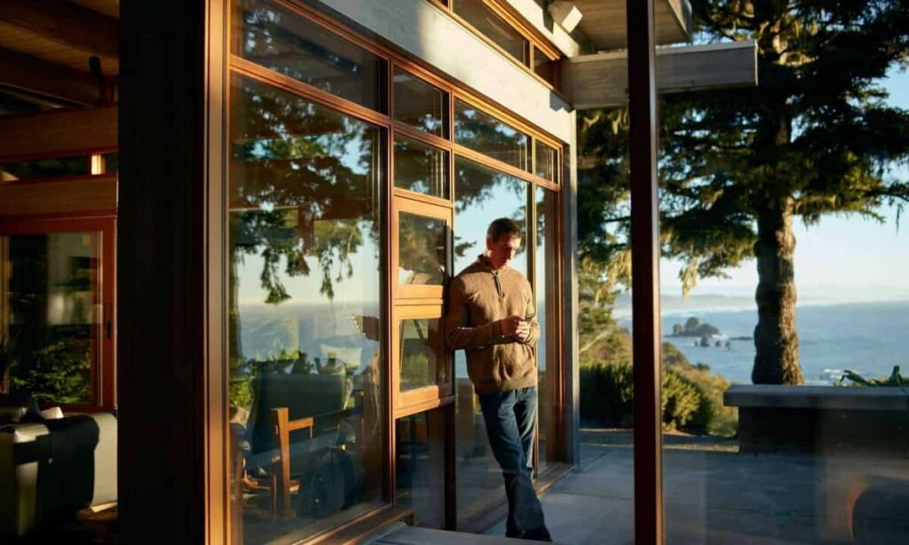 Is BCE Still a Buy? Here’s My Verdict person on phone leaning against outside wall with scenic view at airbnb rental property